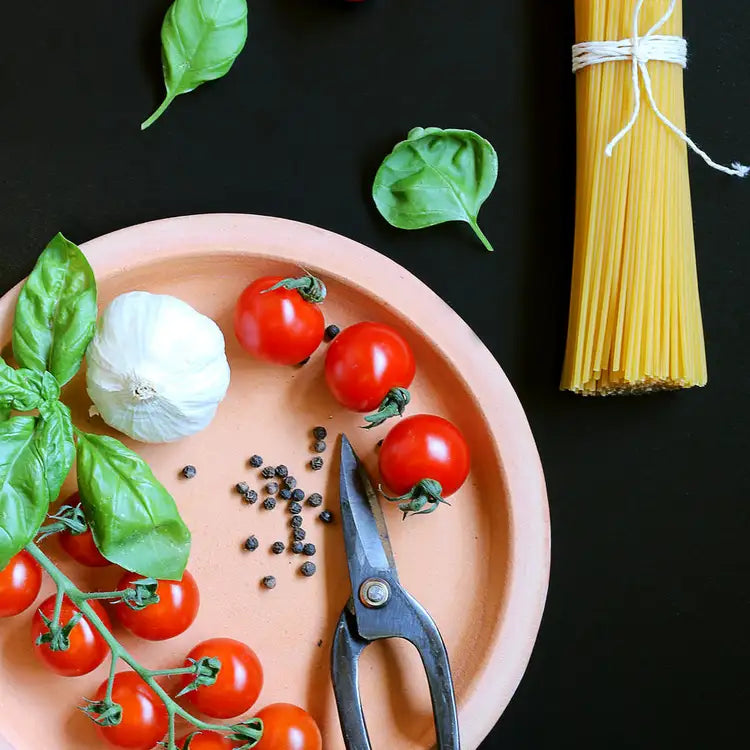 un plato rosa con una tijera y tomates cherry